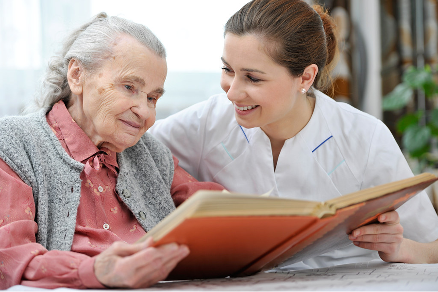 An older woman looking at a book with a healthcare professional. 